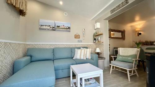 un salon avec un canapé bleu et une table dans l'établissement Cabane du Pêcheur, maison avec extérieur, au Crotoy