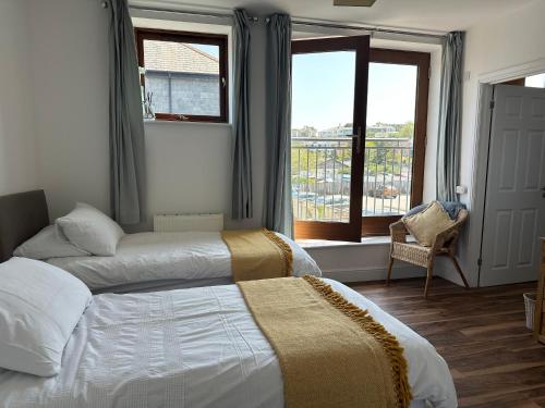 two beds in a hotel room with a window at Tidemill House Apartment in Falmouth