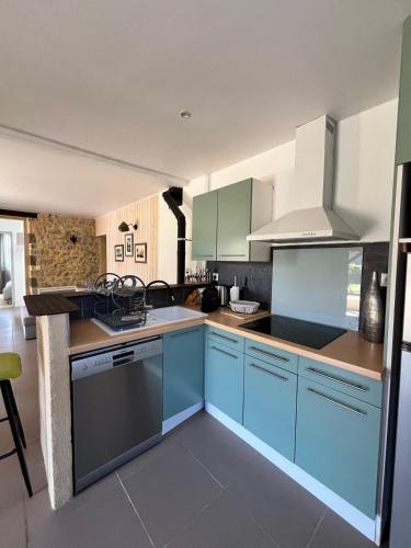 La cuisine est équipée de placards bleus et d'un four avec plaques de cuisson. dans l'établissement La maison d'Alice, à Sarlat-la-Canéda