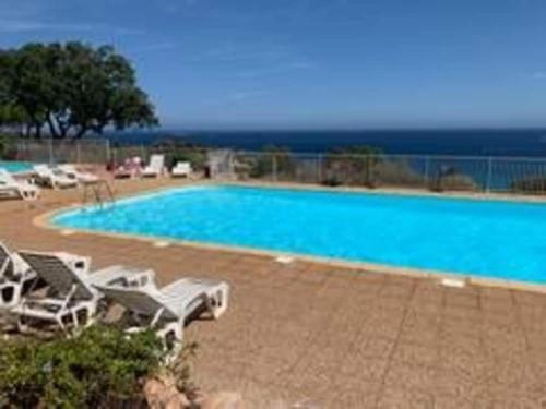 - une grande piscine bordée de chaises longues blanches dans l'établissement Logement A Nepita splendide vue mer avec piscine, à Porto-Vecchio
