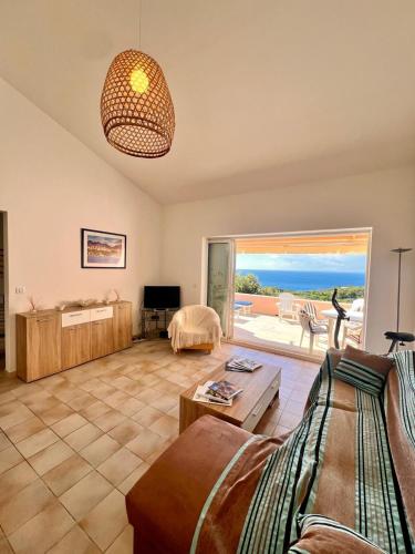 un salon avec un canapé et une vue sur l'océan dans l'établissement Logement A Nepita splendide vue mer avec piscine, à Porto-Vecchio