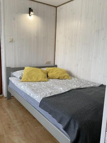 a bed with two yellow pillows in a bedroom at Domki Pod Jarzębiną Borsk in Borsk