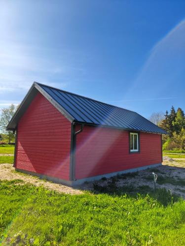 a red barn in a field of grass at Family vacation, 2 bedroom house - Red House in Lõupõllu