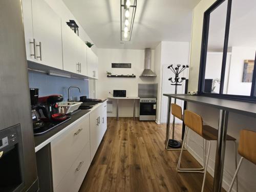 une cuisine avec des armoires blanches et un plancher en bois dans l'établissement L'atelier des Reves, à Fécamp