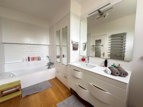une salle de bain avec un lavabo, une baignoire et un miroir dans l'établissement Maison spacieuse et élégante vue sur l'etang de Lannenec à 600m du Fort-Bloqué, à Ploemeur