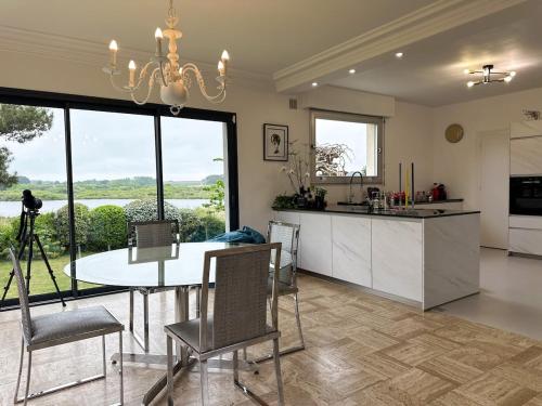une cuisine et une salle à manger avec une table et des chaises dans l'établissement Maison spacieuse et élégante vue sur l'etang de Lannenec à 600m du Fort-Bloqué, à Ploemeur