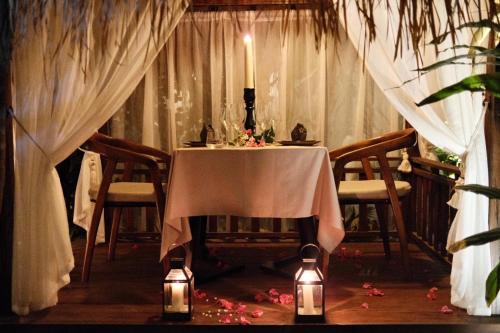 a table with a candle in a room with curtains at Hani Hideaway in Gili Air