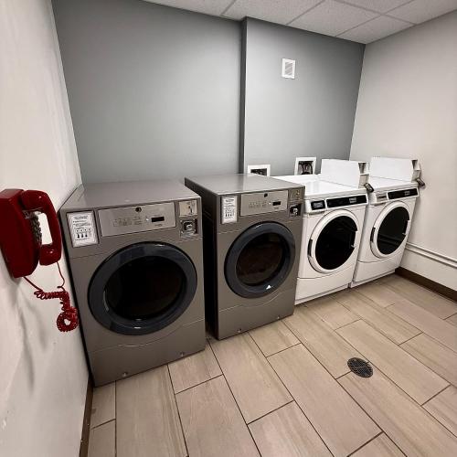a laundry room with three washing machines and a phone at Sleep Inn & Suites Denver International Airport in Denver