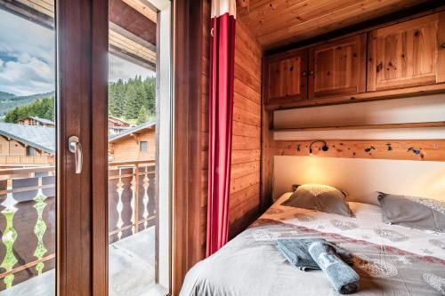 a bedroom with a bed and a large window at La Flèche d'Or in Châtel