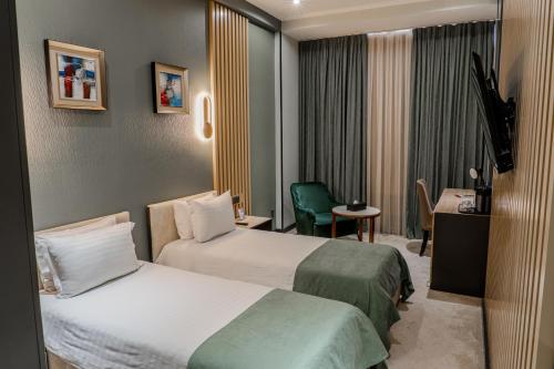 a hotel room with two beds and a desk at HUSMA Hotel & Spa in Tashkent