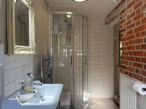ein Badezimmer mit Waschbecken und Glasdusche in der Unterkunft Dairy Cottage Luxury B&B in Attleborough