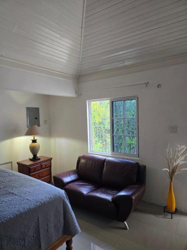 a living room with a leather couch and a window at Sunset 22 by the Airport Apt#6 in Montego Bay