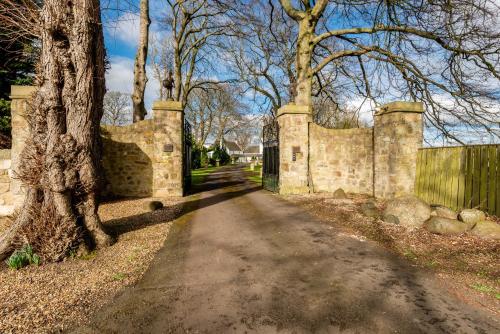 a stone wall next to a tree and a road at Castle Gogar Cottage in Edinburgh