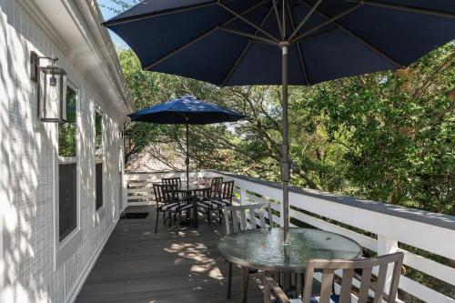 a porch with tables and chairs and an umbrella at Dog Friendly Hot Tub Walk to Beach in Southern Shores