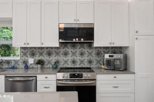 a kitchen with white cabinets and a stove and microwave at Dog Friendly Hot Tub Walk to Beach in Southern Shores