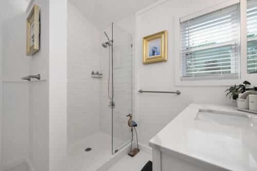 a white bathroom with a shower and a sink at Dog Friendly Hot Tub Walk to Beach in Southern Shores