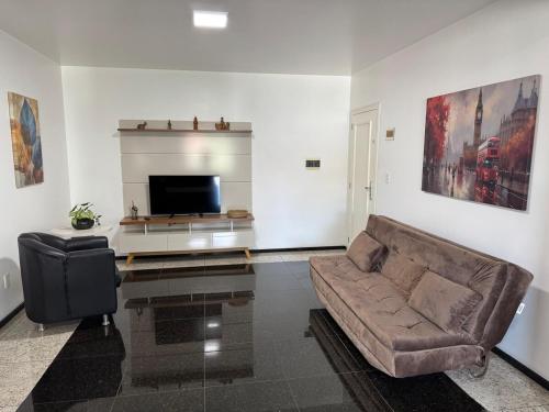 a living room with a couch and a flat screen tv at Hospedaria Sewald in Treze Tílias