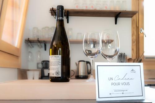a bottle of wine sitting next to two wine glasses at Chalet plein sud 10 personnes garage privé cheminée in La Salle Les Alpes