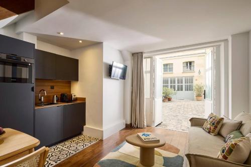 un salon avec un canapé et une cuisine dans l'établissement Un 1-Ch/1-SdB Confortable- Place des Vosges, à Paris