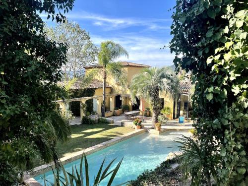 une piscine devant une maison avec des palmiers dans l'établissement Mas Saint Anne, à Évenos