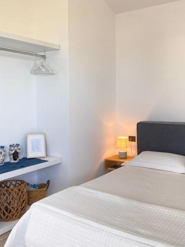 a white bedroom with a bed and a table and a lamp at Nacàri Home in Giardini Naxos