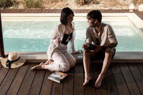 a man and a woman sitting next to a swimming pool at Luna Minoica Suites and Apartments in Montallegro