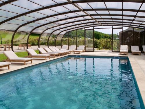an indoor pool with lounge chairs and a glass house at Résidence hôtelière et SPA des sources du gros noyer in Malaucène