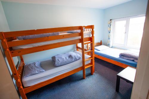 two bunk beds in a room with a window at Breakwater Hostel in Newquay