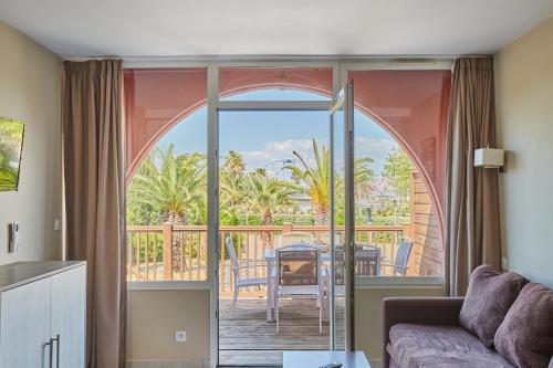 d'un salon avec un canapé et un balcon. dans l'établissement Résidence Odalys Du Golfe, au Cap d'Agde