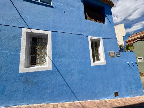 a blue building with two windows on a street at Ignis Rural Apartment - Casillas Valle de Ayora in Jalance