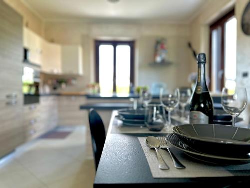a dining table with a bottle of wine and glasses at Appartamento in villa con piscina privata e vasca idromassaggio ad uso esclusivo in Rivarolo Canavese