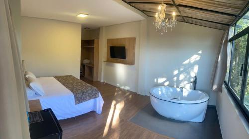 a bedroom with a tub and a bed and a television at Village de Charme - 2km do Capivari in Campos do Jordão