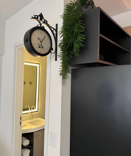 a clock hanging on a wall next to a bathroom at Studio Concept Avenida das Esmeraldas in Marília