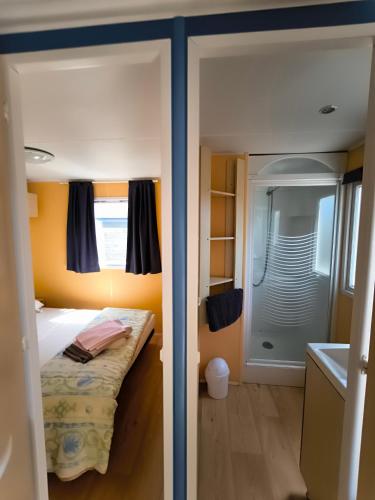 a small bedroom with a bed and a shower at Village Vacances Les Sables d'Or in Gouville-sur-Mer