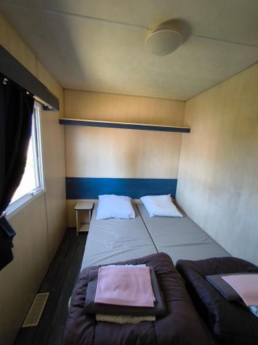 a small room with two beds and a window at Village Vacances Les Sables d'Or in Gouville-sur-Mer