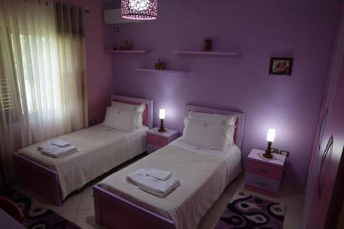 two beds in a room with purple walls and lights at Villa Nano in Berat