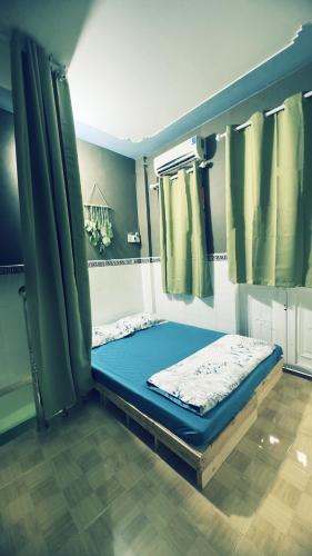 a small bed in a room with green curtains at Lam NguyenVn Minihouse in Can Tho
