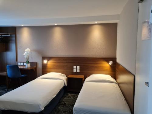 une chambre d'hôtel avec deux lits et un bureau dans l'établissement Hôtel Arcades, à Lourdes