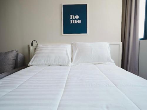 a bed with white sheets and a picture on the wall at Apê Santos Praia do Gonzaga in Santos