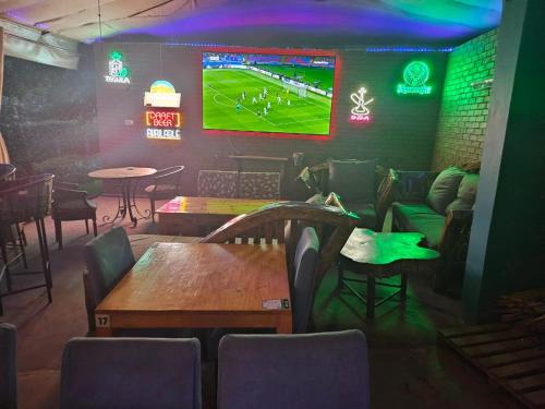 a bar with tables and chairs and a tv on the wall at Boulevard Inn Mt Meru in Arusha