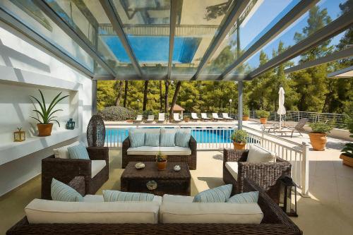 Una sala de estar con un invernadero con muebles y una piscina. en Hera's Resort with Private Pool and Lush Garden, en Sani Beach