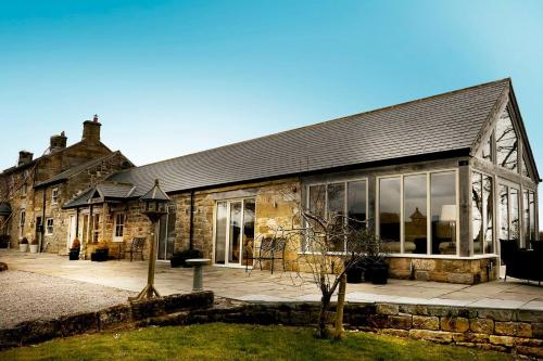 ein altes Steingebäude mit großen Glasfenstern in der Unterkunft Hillock's Farm Cottage, Luxury in Moorsholm