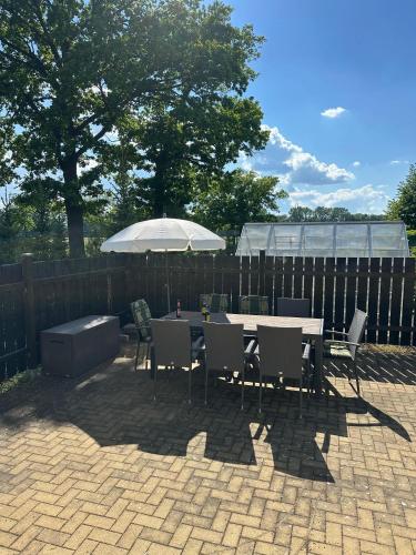 a patio with a table and chairs and an umbrella at Charmantes Studio Ferienhaus mit Garten & Netflix Nähe Spreewald in Heinersbrück