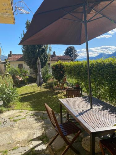 a picnic table with an umbrella and a table and chairs at La Casina in Maccagno con Pino e Veddasca