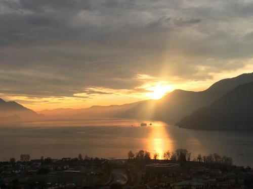 a sun setting over a body of water with mountains at La Casina in Maccagno con Pino e Veddasca