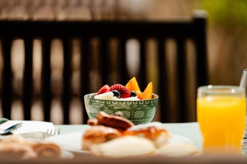 a bowl of fruit on a table with a glass of orange juice at Hotel Rural Binigaus Vell in Es Migjorn Gran
