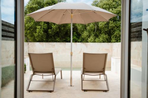 two chairs and an umbrella on a patio at Hotel Rural Binigaus Vell in Es Migjorn Gran