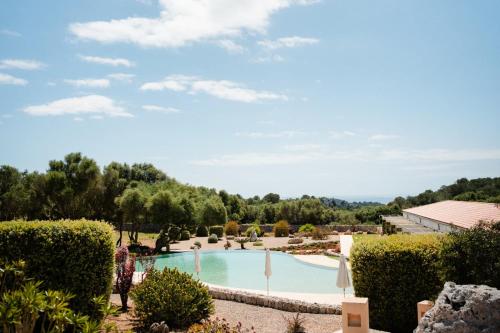 a person standing in front of a swimming pool at Hotel Rural Binigaus Vell in Es Migjorn Gran