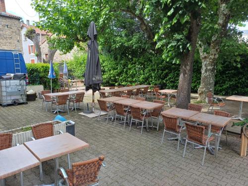 un groupe de tables et de chaises avec un parapluie dans l'établissement Auberge des Platanes, à Villevocance
