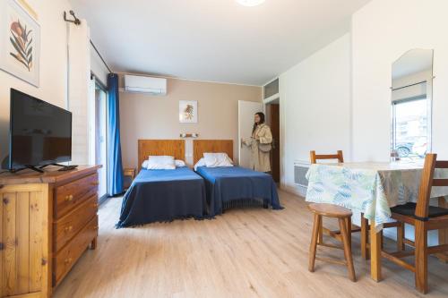 a bedroom with a bed and a woman standing in the window at Les Mimosas - App 05 - Appartement Cosy RDC in Cazaubon